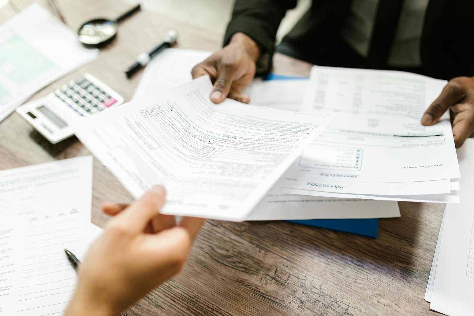 Two office professionals exchanging printed documents representing email compliance records.