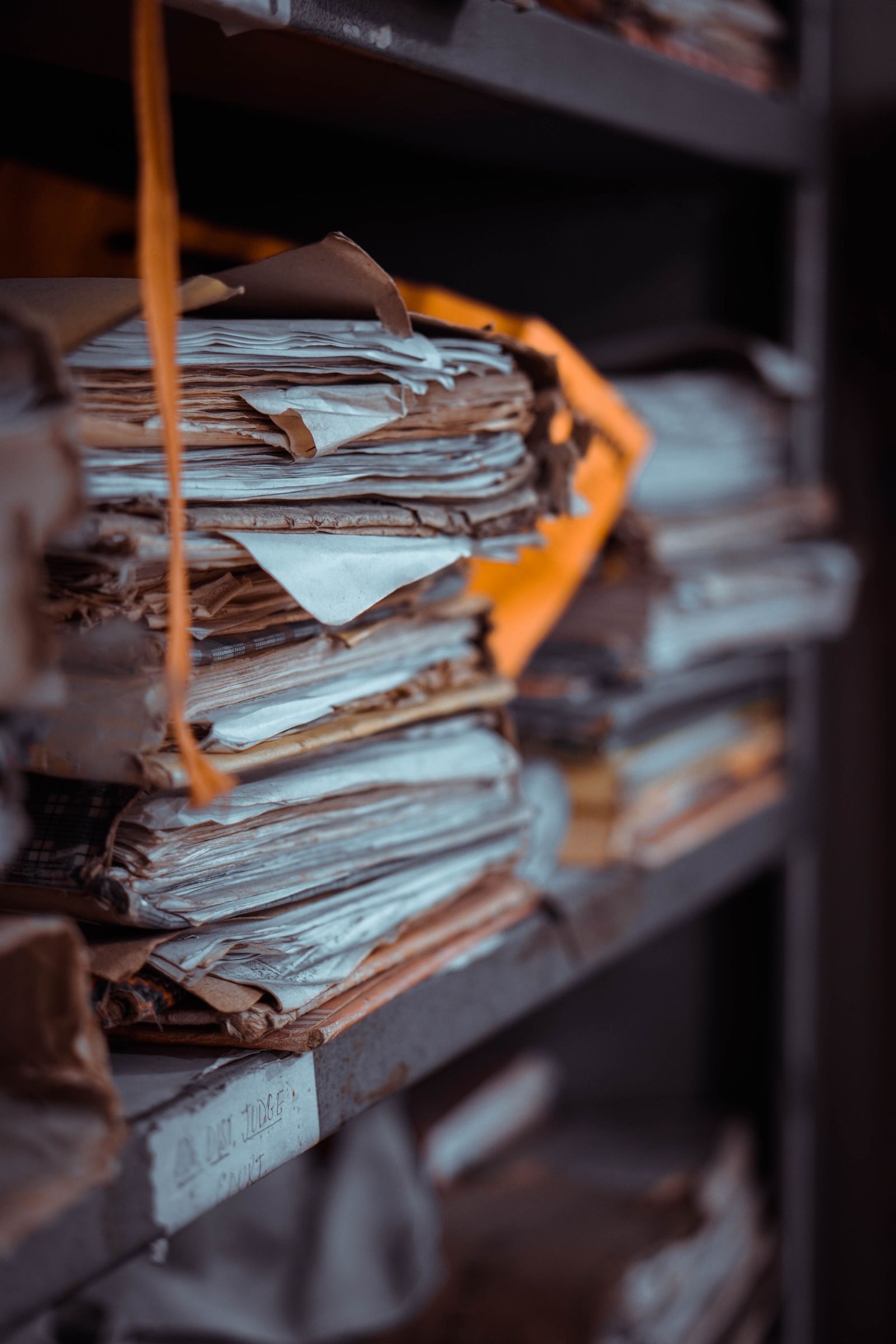 Stacks of old documents and papers piled on shelves for long-term records archiving.